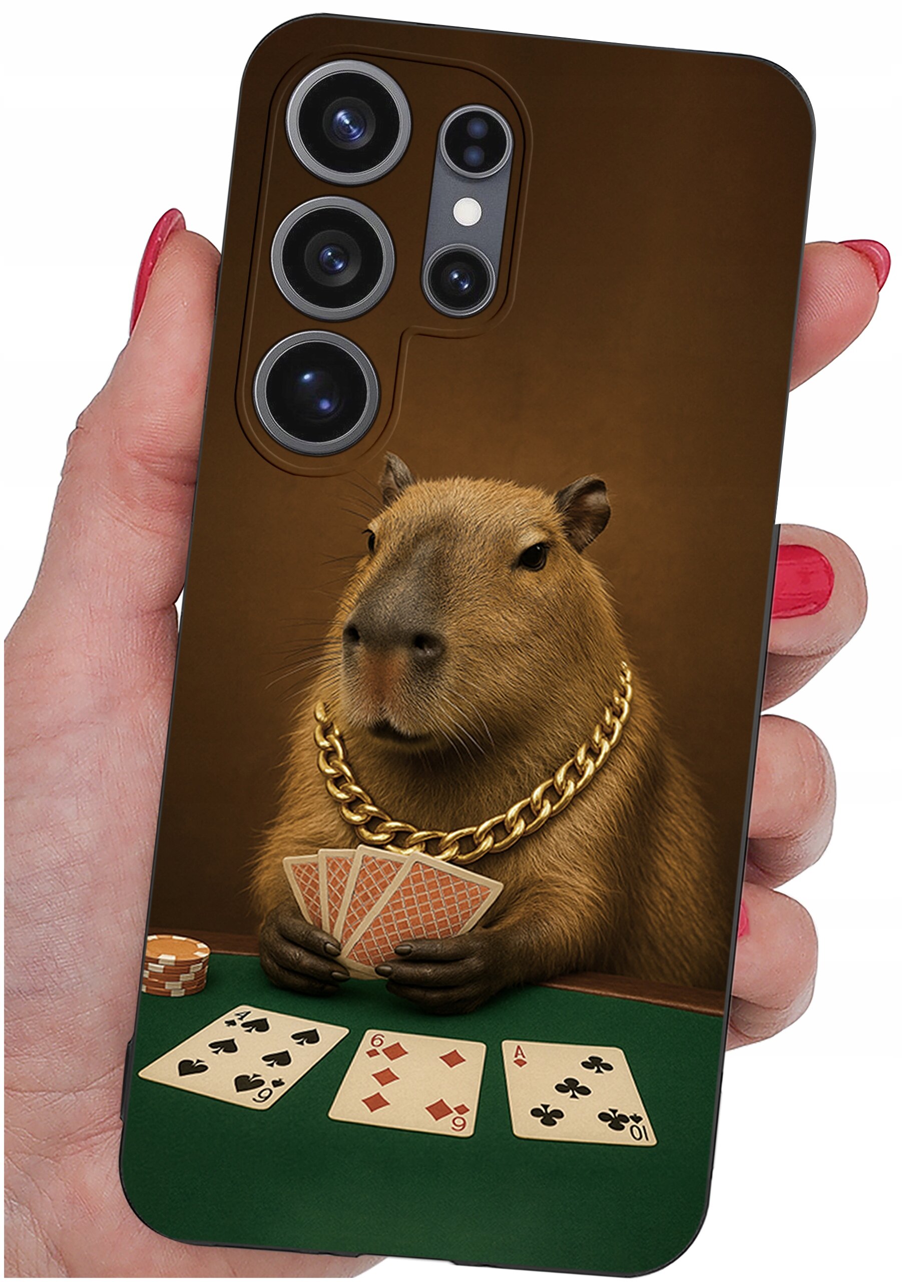 Etui na telefon z nadrukiem kapibary w złotym łańcuchu, trzymającej karty do gry. Na stole widoczne są trzy odkryte karty i żetony pokerowe.