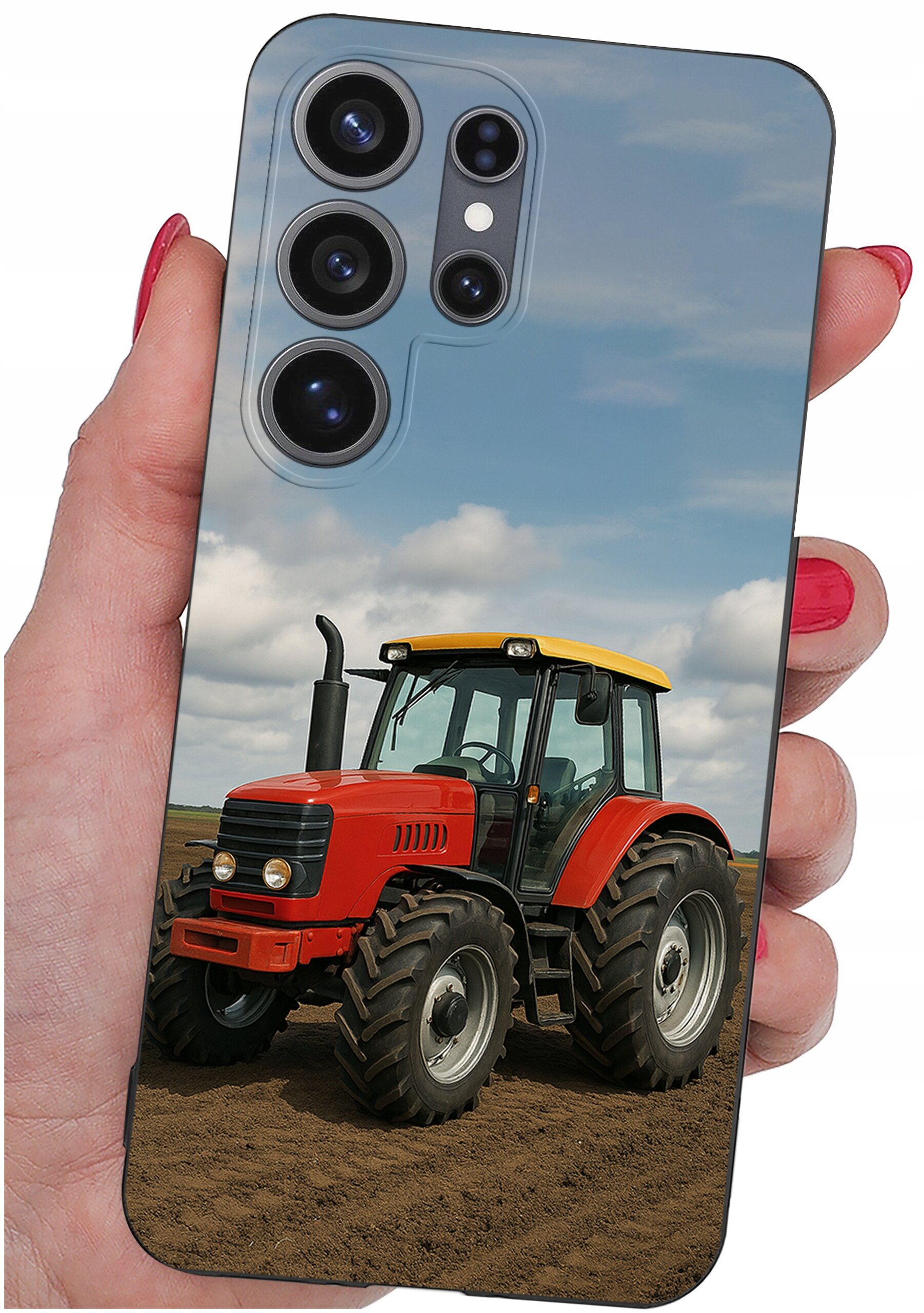 Etui na telefon z nadrukiem czerwonego traktora na tle pola i nieba, trzymane w dłoni z pomalowanymi na czerwono paznokciami.