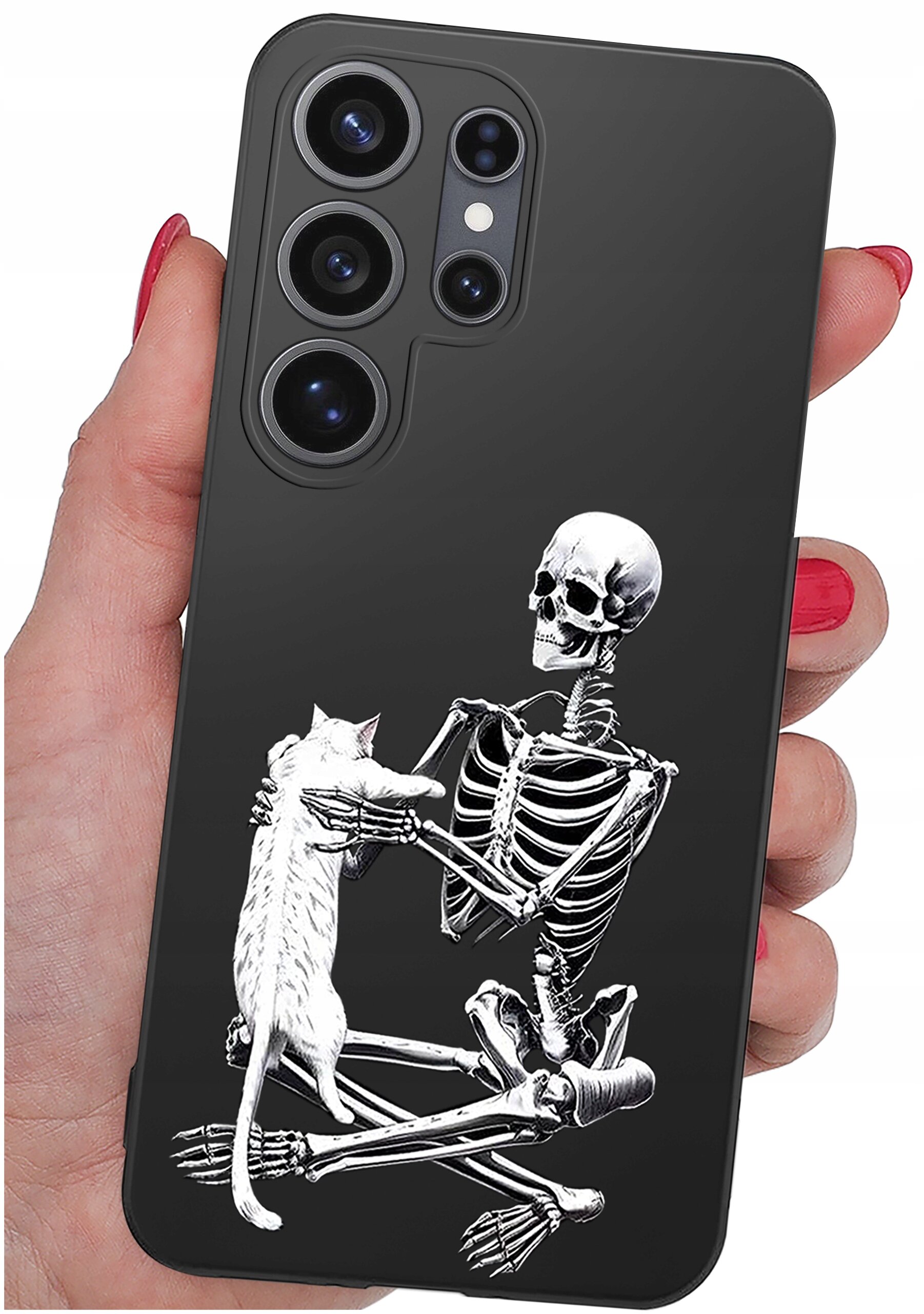 Czarne etui na telefon z nadrukiem szkieletu trzymającego kota. Etui jest trzymane w dłoni z pomalowanymi na czerwono paznokciami.