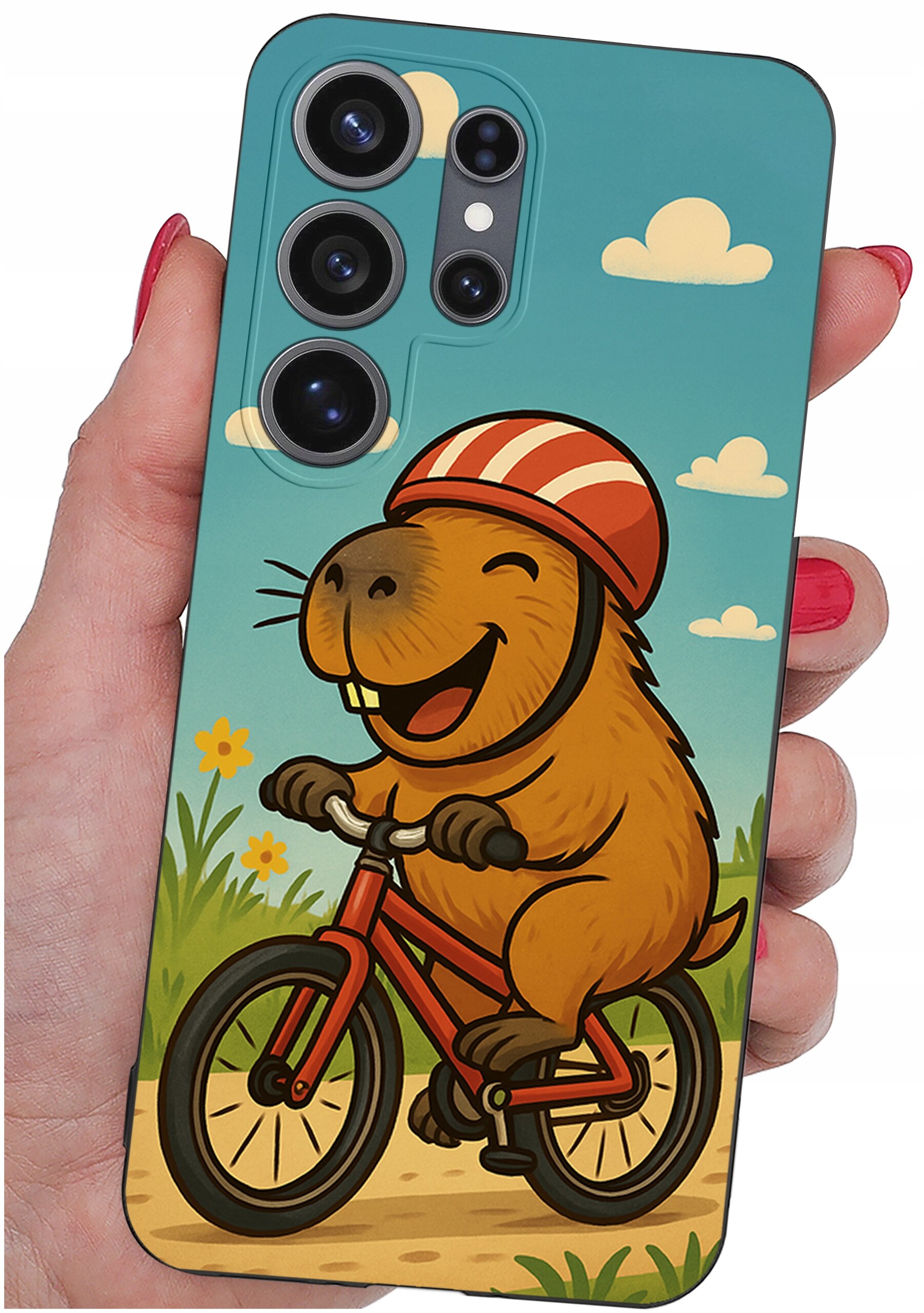 Etui na telefon z kolorowym rysunkiem uśmiechniętego zwierzęcia na rowerze w kasku, na tle nieba z chmurkami i kwiatami. Etui trzymane jest w dłoni, a na górze widoczne są otwory na aparat.