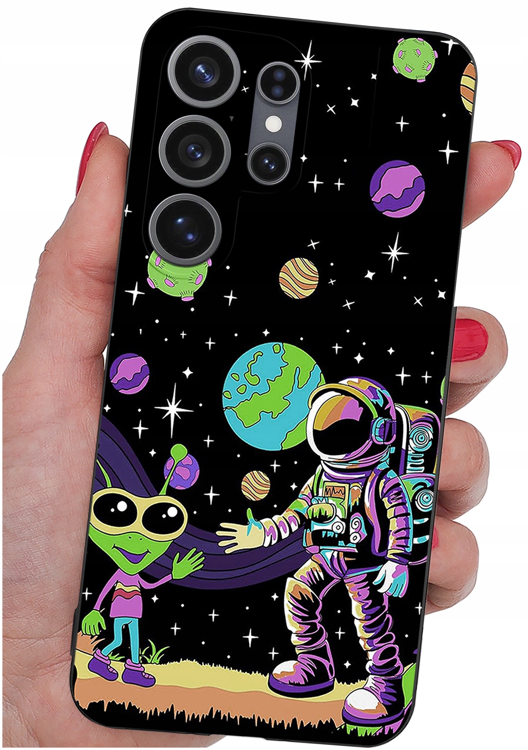 Etui na telefon z kolorowym wzorem przedstawiającym kosmonautę i zielonego kosmitę na tle kosmosu z planetami i gwiazdami. Etui jest trzymane w dłoni z pomalowanymi na czerwono paznokciami.