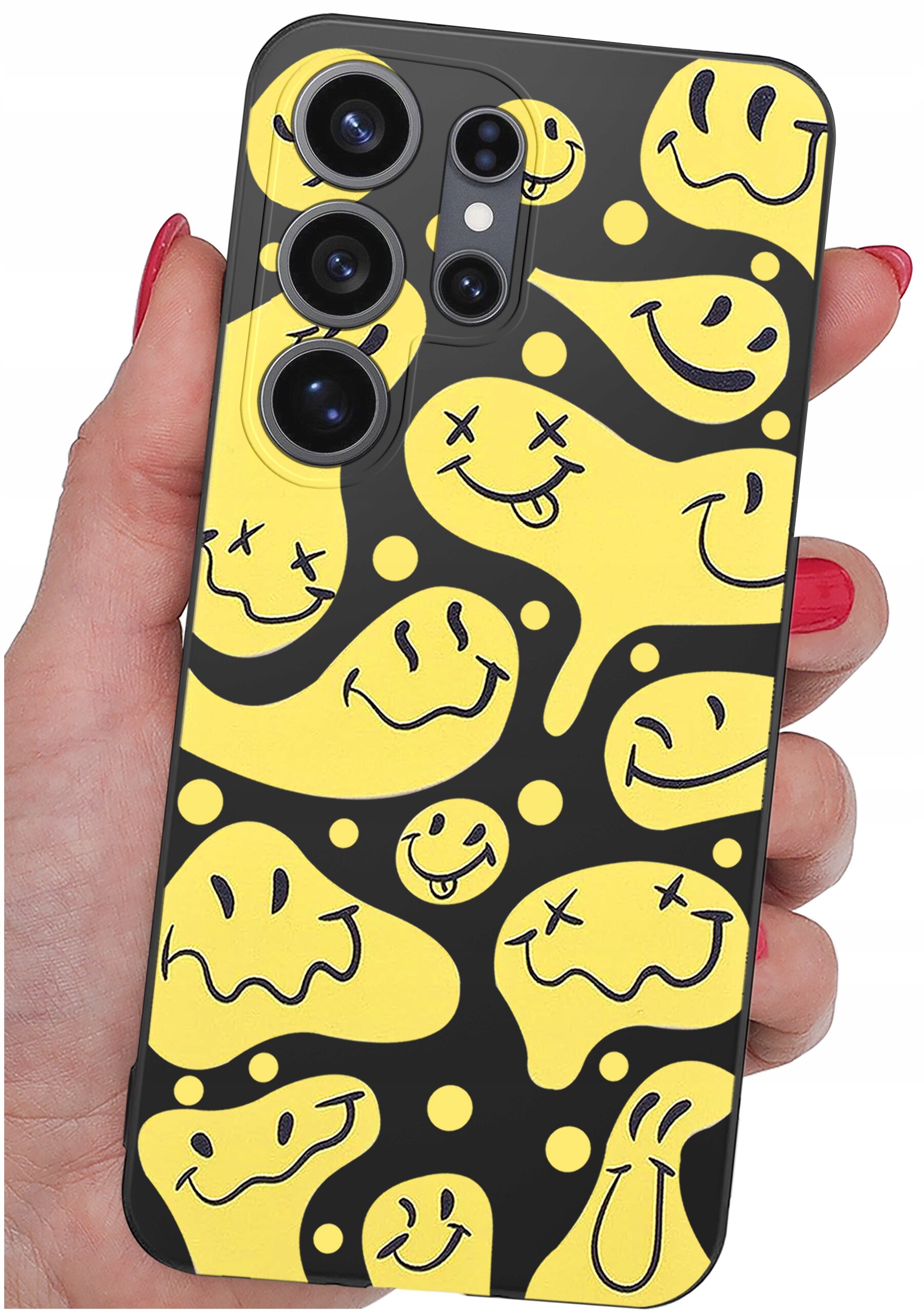 Etui na telefon z żółtym wzorem uśmiechniętych twarzy na czarnym tle, trzymane w dłoni z czerwonymi paznokciami. Widoczne są cztery otwory na aparaty fotograficzne.