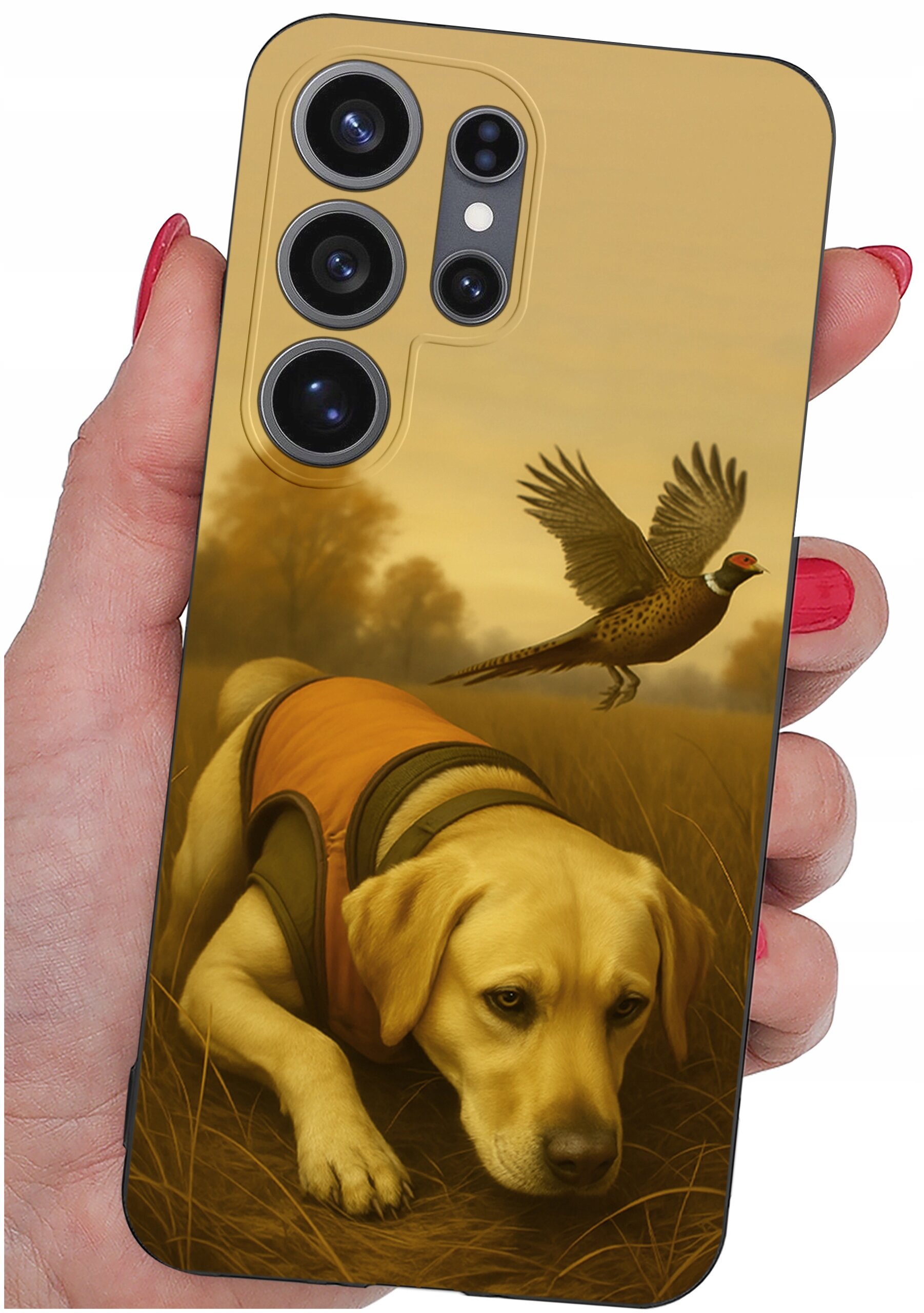 Etui na telefon z nadrukiem przedstawiającym psa w pomarańczowej kamizelce oraz lecącego bażanta na tle jesiennego krajobrazu. Etui trzymane jest w dłoni z pomalowanymi na czerwono paznokciami.