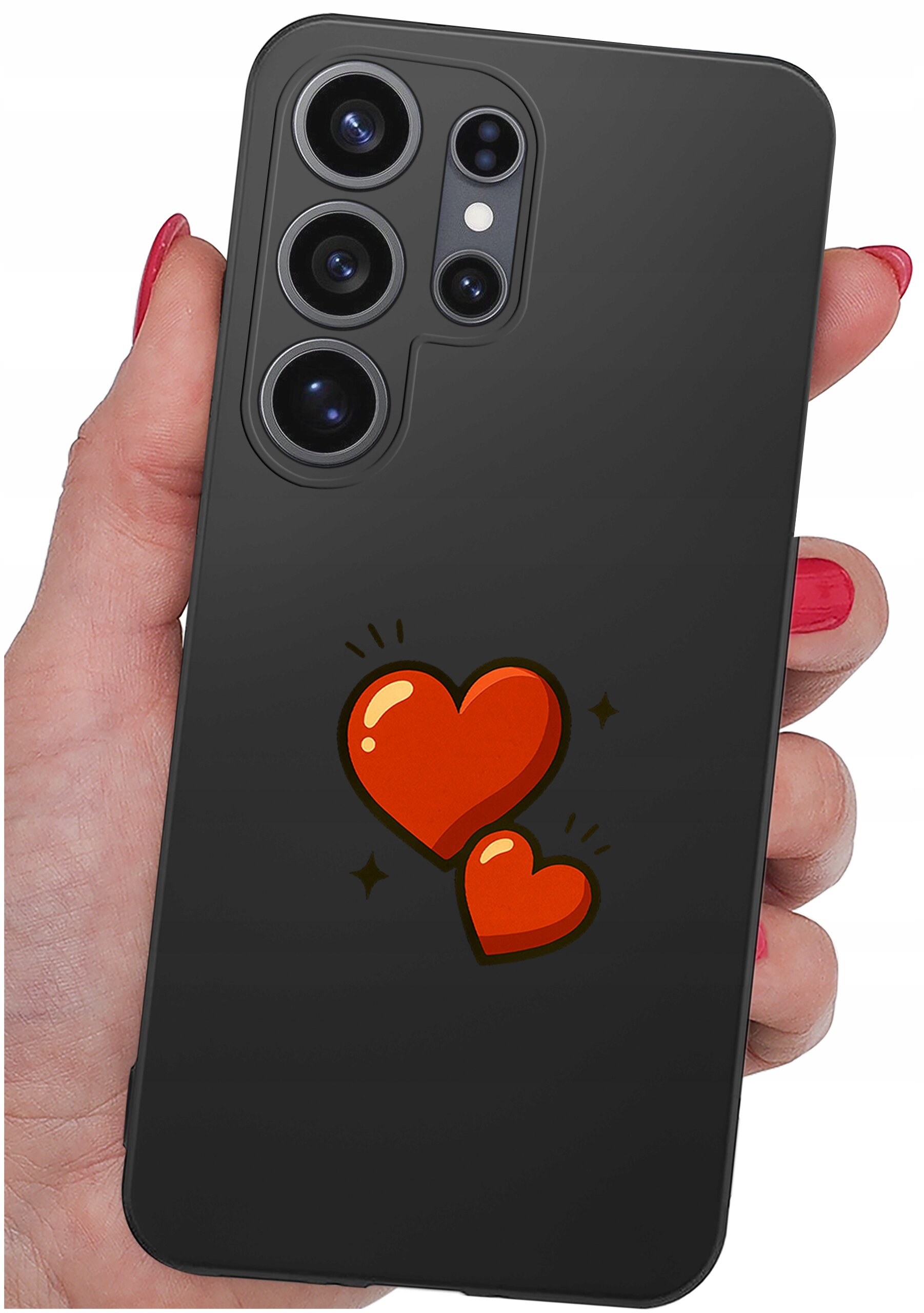 Czarne etui na telefon z trzema dużymi obiektywami aparatu i grafiką dwóch czerwonych serc na tylnej części. Etui trzymane jest w dłoni z pomalowanymi na czerwono paznokciami.