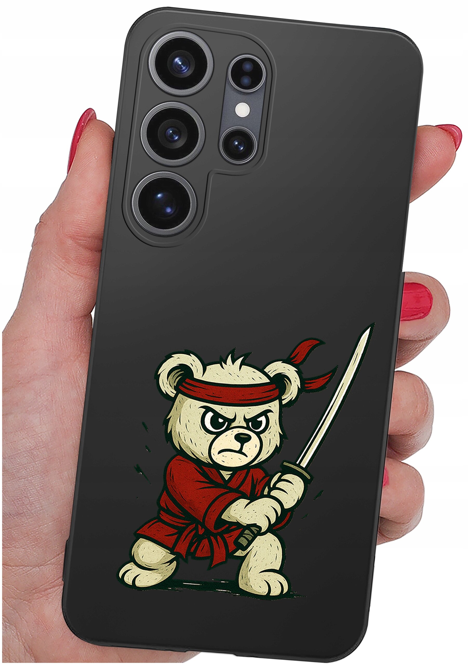 Osoba trzyma telefon z czarnym etui, na którym znajduje się rysunek misia w czerwonym stroju z mieczem. Etui ma wycięcia na cztery obiektywy aparatu.