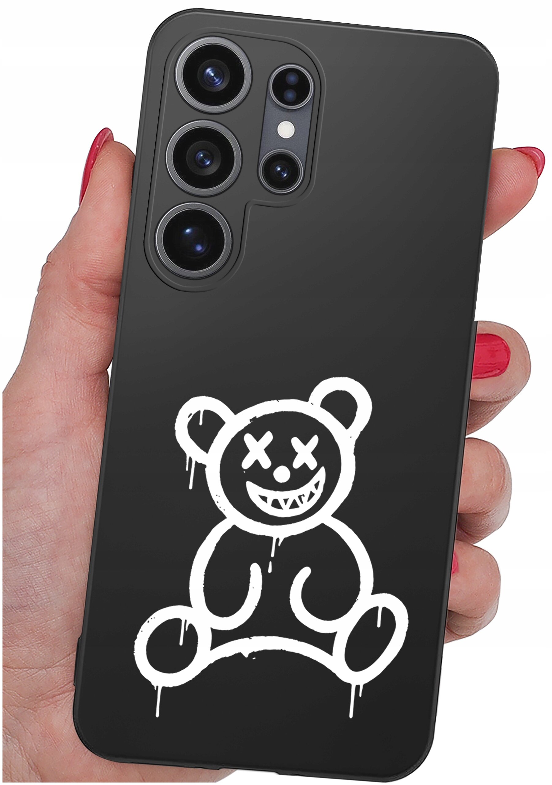 Czarne etui na telefon z białym rysunkiem misia o skrzyżowanych oczach i szerokim uśmiechu. Etui trzymane jest w dłoni z pomalowanymi na czerwono paznokciami.