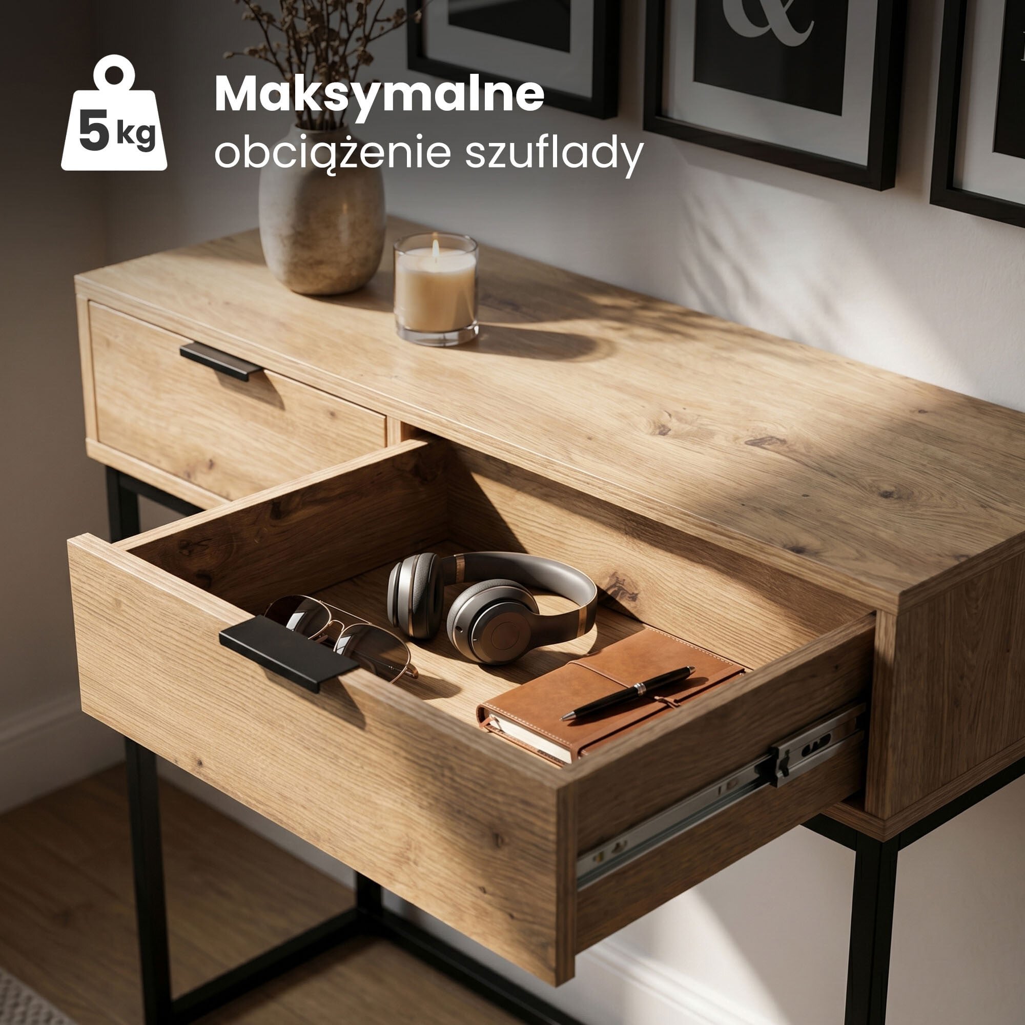 Drewniany stolik z otwartą szufladą, w której znajdują się słuchawki, okulary przeciwsłoneczne i notes z długopisem. Na blacie stoi świeca i wazon z gałązkami, a w rogu widoczny jest tekst: \'Maksymalne obciążenie szuflady 5 kg\'.