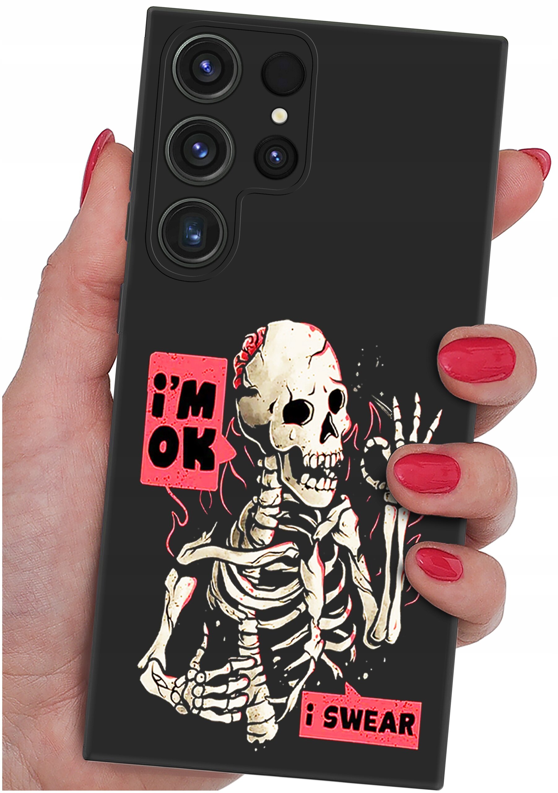 Czarna obudowa telefonu z nadrukiem szkieletu i napisami \'i\'m OK\' oraz \'i SWEAR\'. Obudowa trzymana jest w dłoni z pomalowanymi na czerwono paznokciami.