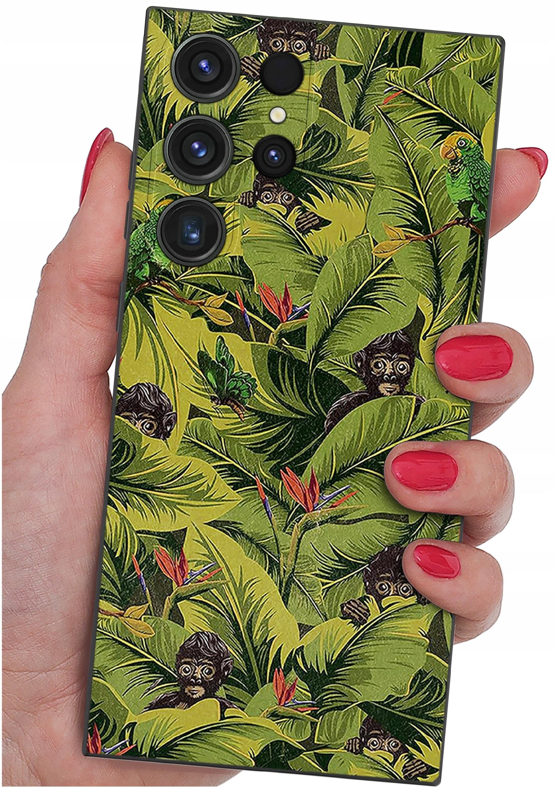 Etui na telefon z motywem tropikalnym, przedstawiające zielone liście, małpy i papugi. Etui trzymane jest w dłoni z pomalowanymi na czerwono paznokciami.