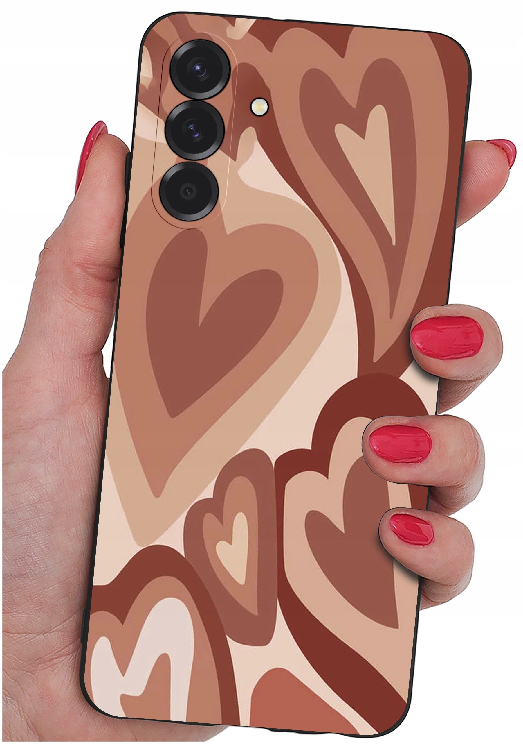 Etui na telefon z wzorem w brązowe serca, trzymane w dłoni z pomalowanymi na czerwono paznokciami. Widoczne są trzy obiektywy aparatu i lampa błyskowa.