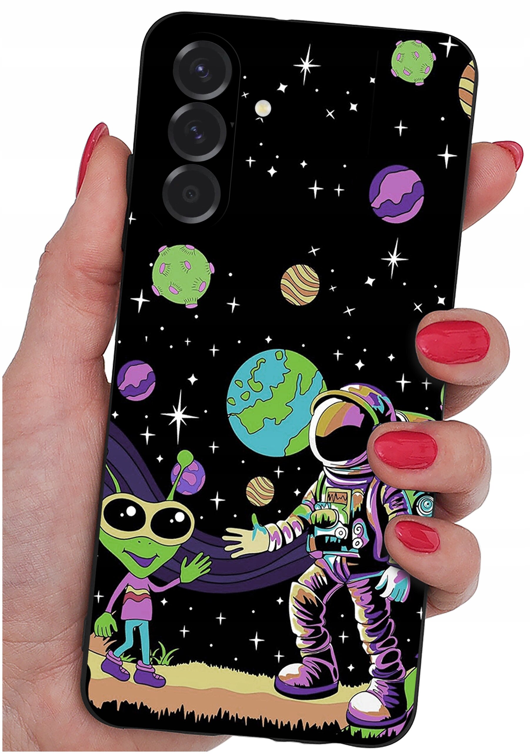 Etui na telefon z kolorowym wzorem przedstawiającym kosmonautę i zielonego kosmitę na tle kosmosu z planetami i gwiazdami. Etui trzymane jest w dłoni z pomalowanymi na czerwono paznokciami.