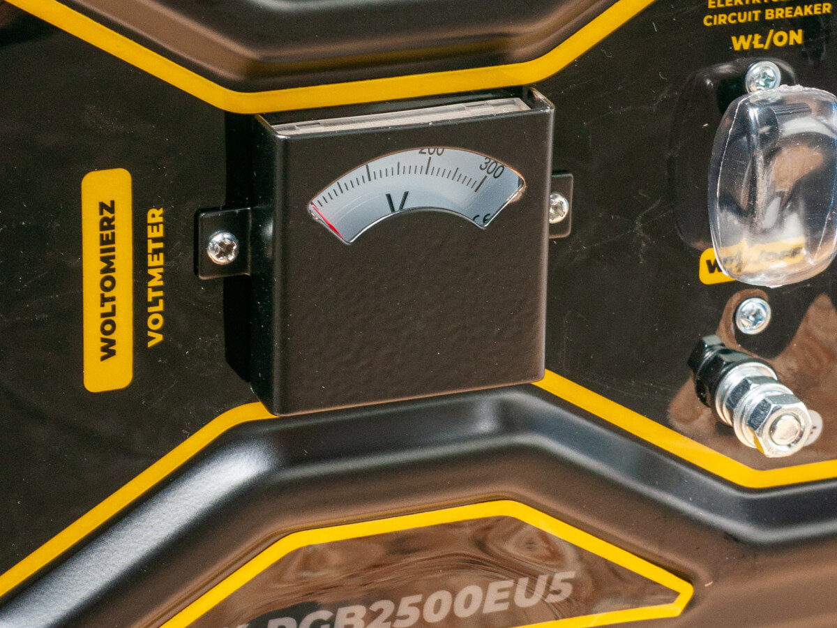 Na obrazie widoczny jest woltomierz z oznaczeniami \'WOLTOMIERZ\' i \'VOLTMETER\', a poniżej znajduje się napis \'PGB2500EU5\'.