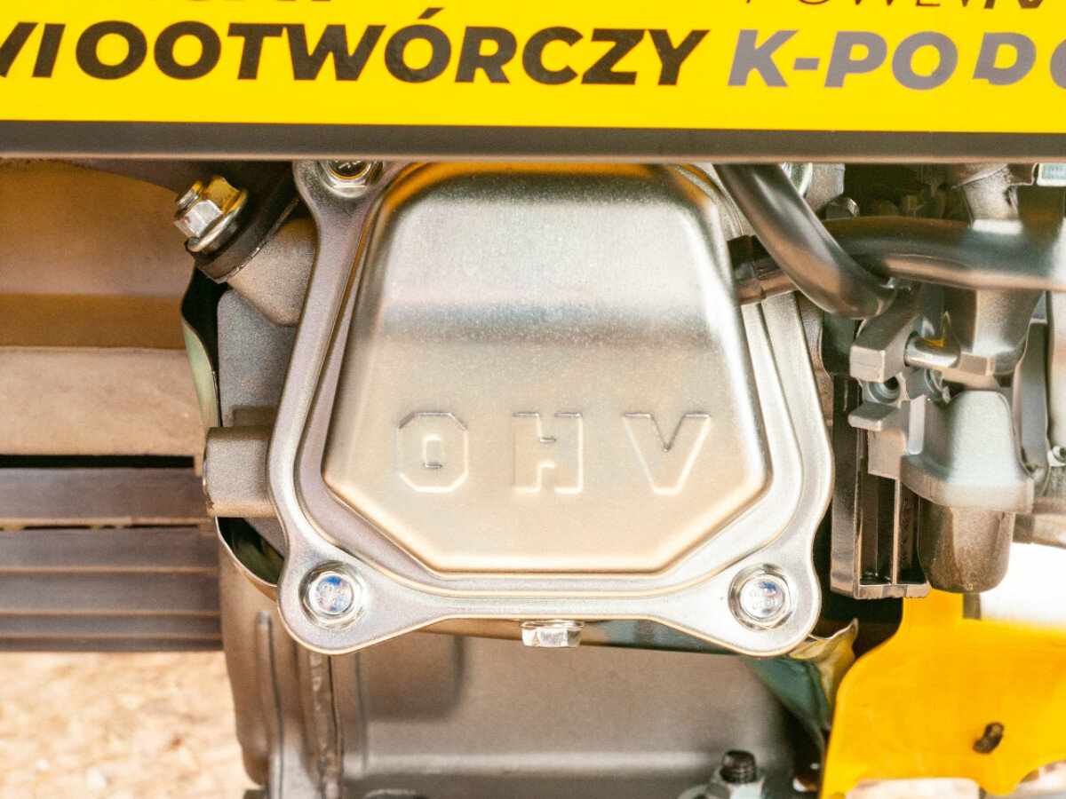 Zbliżenie na metalową część z napisem \'OHV\' oraz fragment żółtej obudowy z częściowym napisem \'WOOTWÓRCZY K-POD\'.