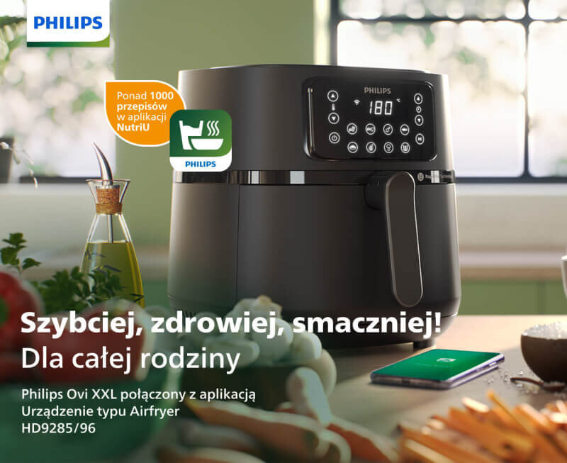 Na obrazie widoczna jest czarna frytkownica beztłuszczowa z wyświetlaczem i przyciskami dotykowymi, obok której znajduje się butelka z oliwą i telefon. Tekst na obrazie: \'Szybciej, zdrowiej, smaczniej! Dla całej rodziny Philips Ovi XXL połączony z aplikacją Urządzenie typu Airfryer HD9285/96\'.