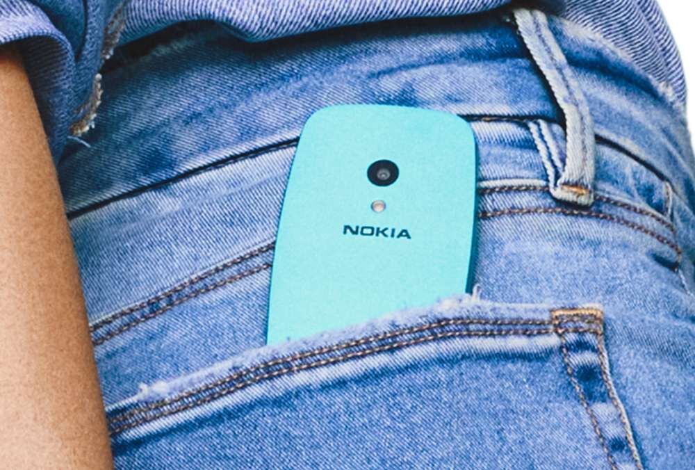 Niebieski telefon z logo NOKIA wystaje z kieszeni dżinsów. Widoczny jest aparat i mały otwór poniżej obiektywu.