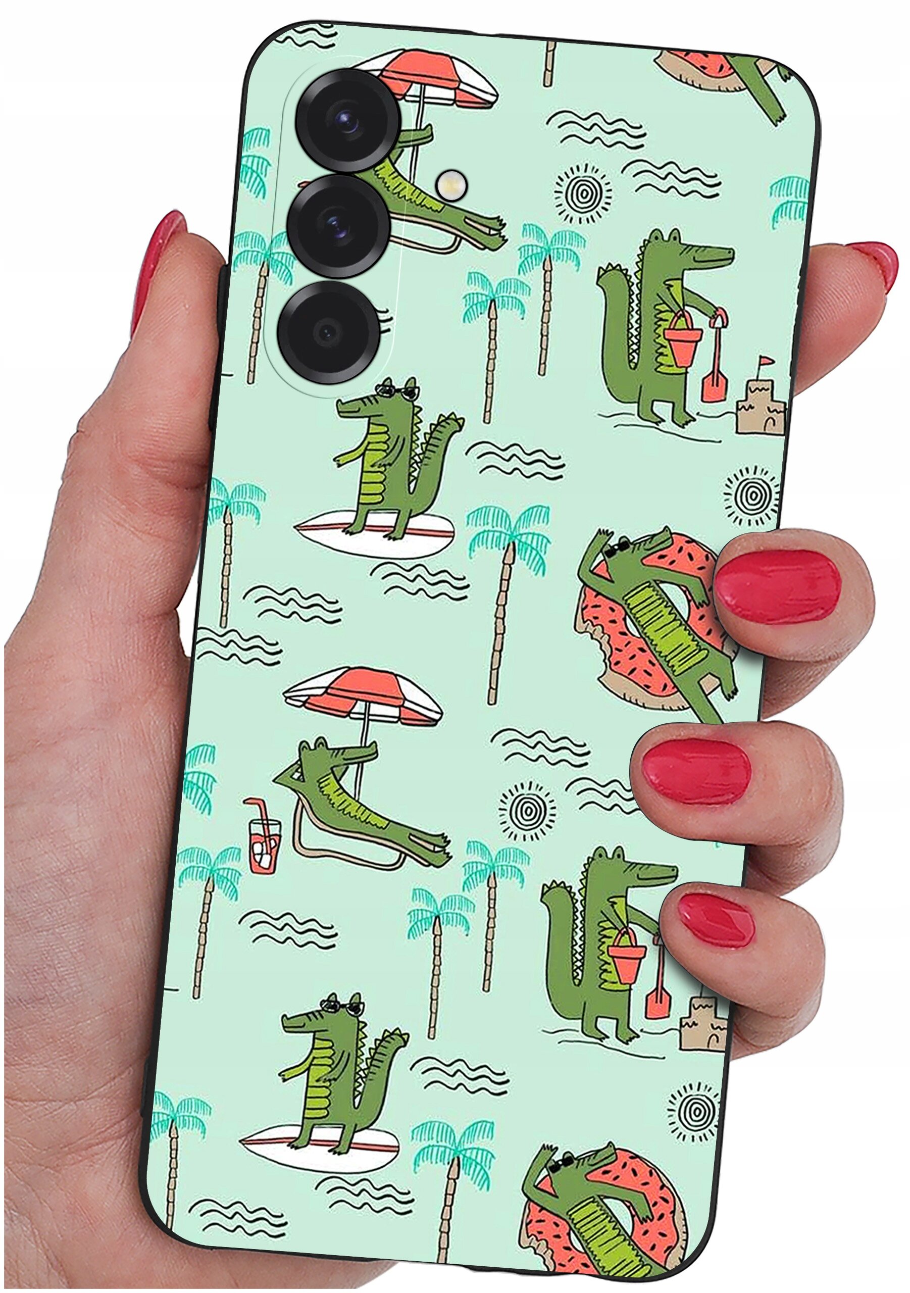 Etui na telefon z wzorem przedstawiającym zielone krokodyle w różnych wakacyjnych scenach, takich jak leżenie na leżaku czy budowanie zamku z piasku. Etui trzymane jest w dłoni z pomalowanymi na czerwono paznokciami.