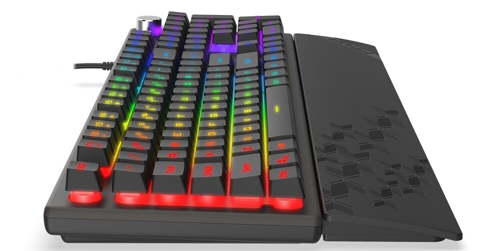 Klawiatura mechaniczna z podświetleniem RGB, widoczna z boku, z podkładką pod nadgarstki ozdobioną geometrycznym wzorem. Na klawiaturze znajduje się pokrętło oraz przewód z wtyczką USB.