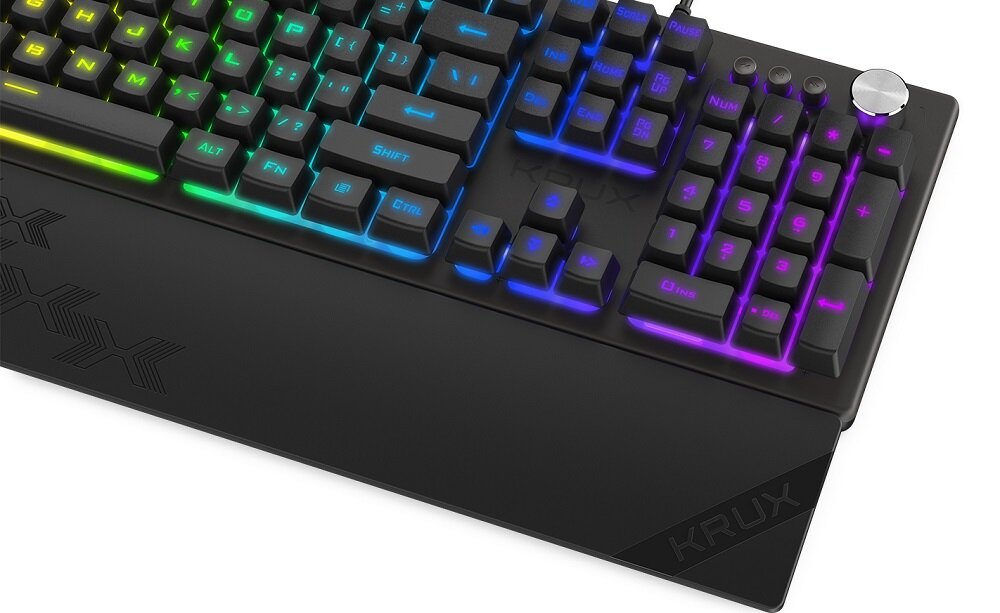 Klawiatura mechaniczna z podświetleniem RGB, widoczne klawisze z różnokolorowym podświetleniem oraz pokrętło w prawym górnym rogu. Na dolnej części klawiatury widoczny jest napis \'KRUX\'.