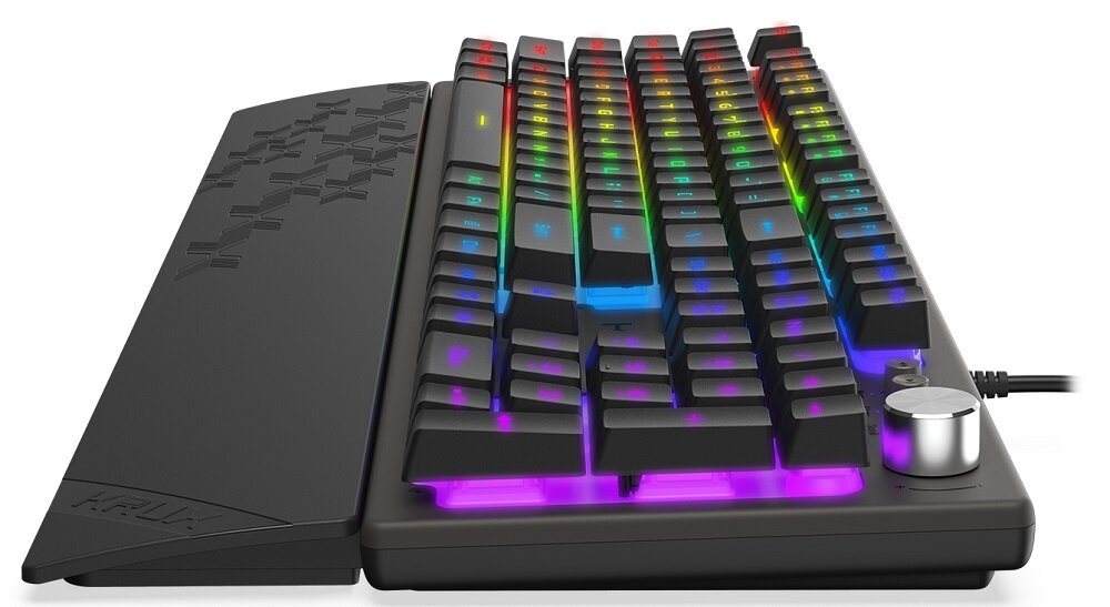 Klawiatura mechaniczna z podświetleniem RGB, posiada dodatkowe pokrętło i podpórkę na nadgarstki z wzorem. Na podpórce widoczne jest logo \'KRUX\'.