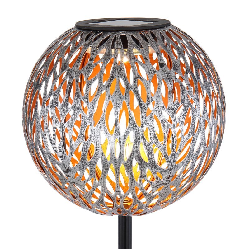 Lampa solarna o kulistym kształcie z ażurowym wzorem, przez który prześwituje ciepłe światło. Górna część lampy posiada panel solarny.