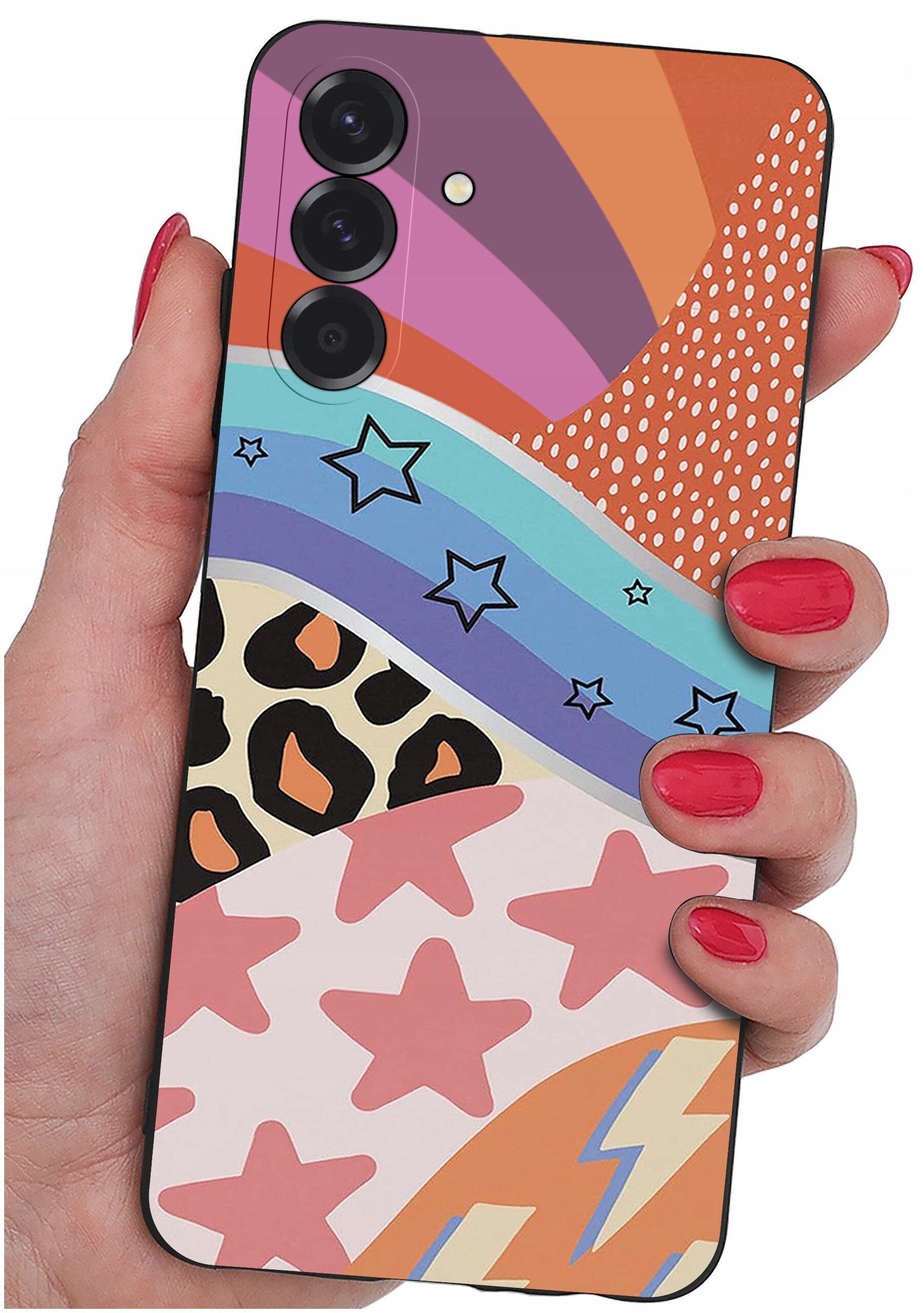 Osoba trzyma telefon z kolorowym etui, które ma wzory w gwiazdy, paski, kropki i motywy zwierzęce. Etui jest wielobarwne z dominującymi odcieniami pomarańczowego, różowego i niebieskiego.