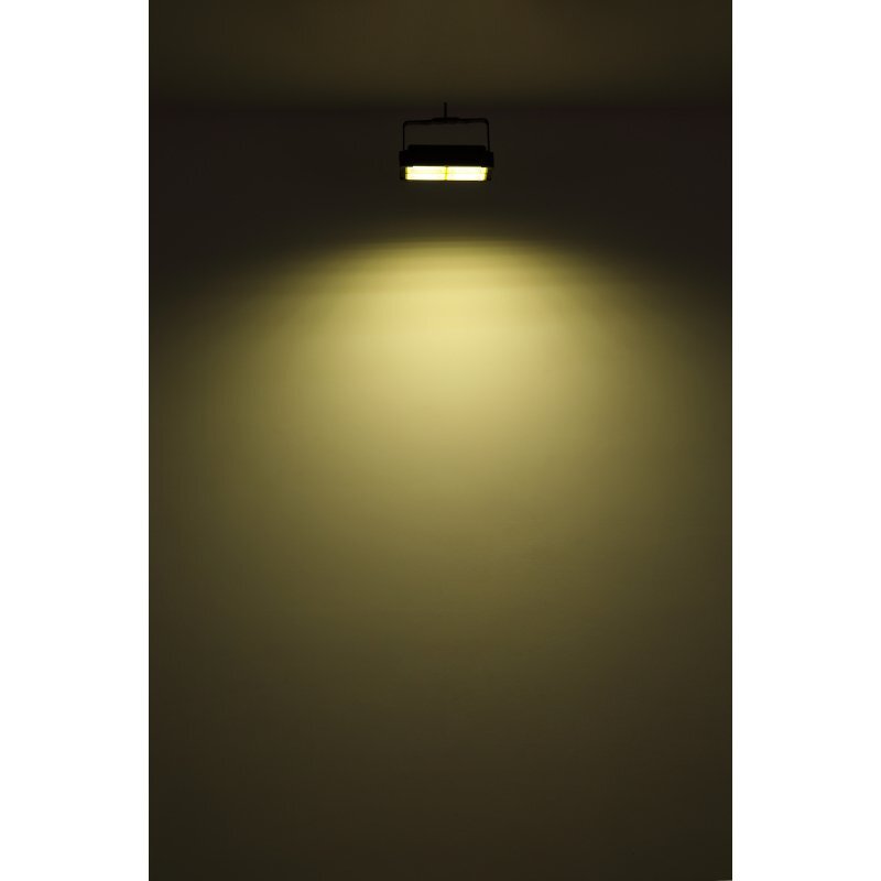 Na obrazie widoczna jest wisząca lampa emitująca ciepłe, żółte światło, oświetlająca ścianę poniżej.