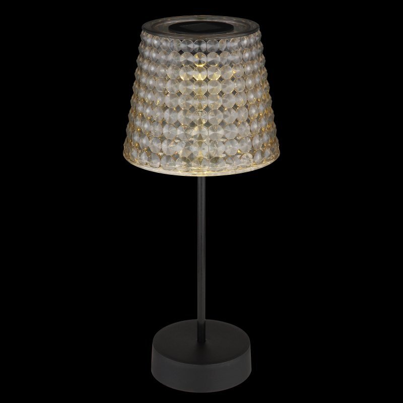 Lampa stołowa LED z przezroczystym, kryształowym kloszem i czarną podstawą. Klosz ma fakturę przypominającą diamenty, a lampa emituje ciepłe światło.