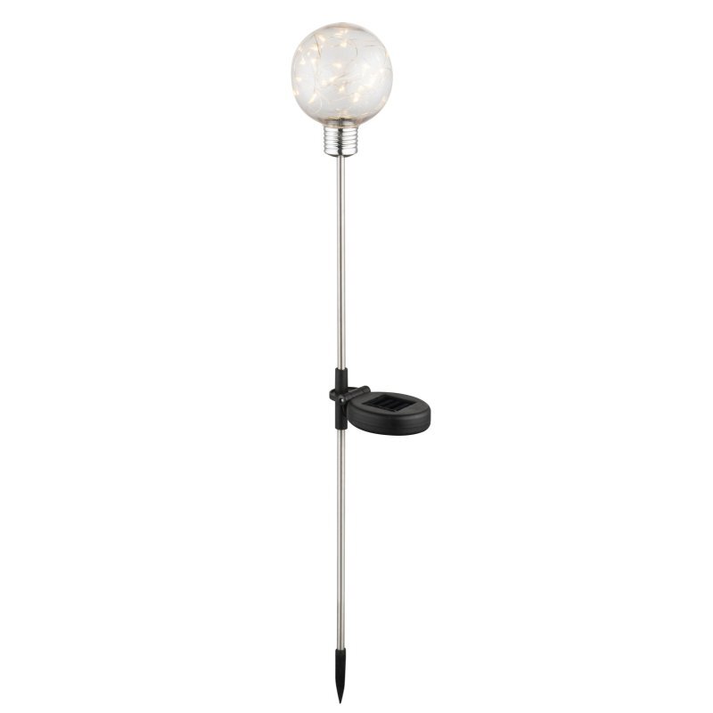 Na obrazie widoczna jest lampa solarna z przezroczystą kulą na szczycie, zamontowana na metalowym pręcie z czarnym panelem solarnym pośrodku. Pręt zakończony jest ostrym końcem do wbicia w ziemię.