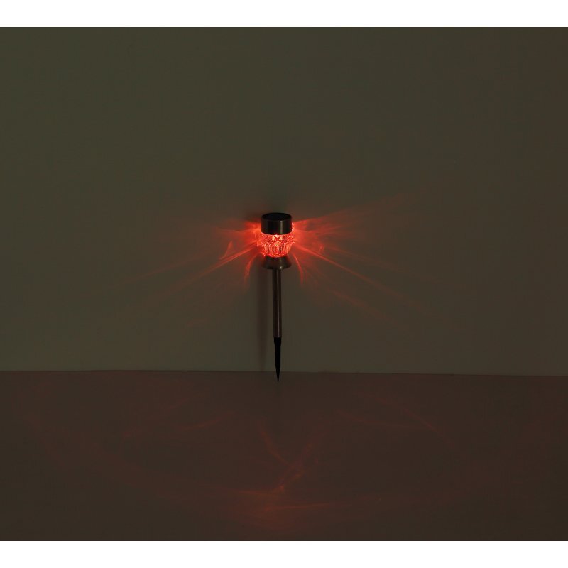 Lampa solarna dogruntowa LED emituje czerwone światło, tworząc rozproszone wzory na ścianie. Lampa ma metalowy trzonek i przezroczysty klosz.