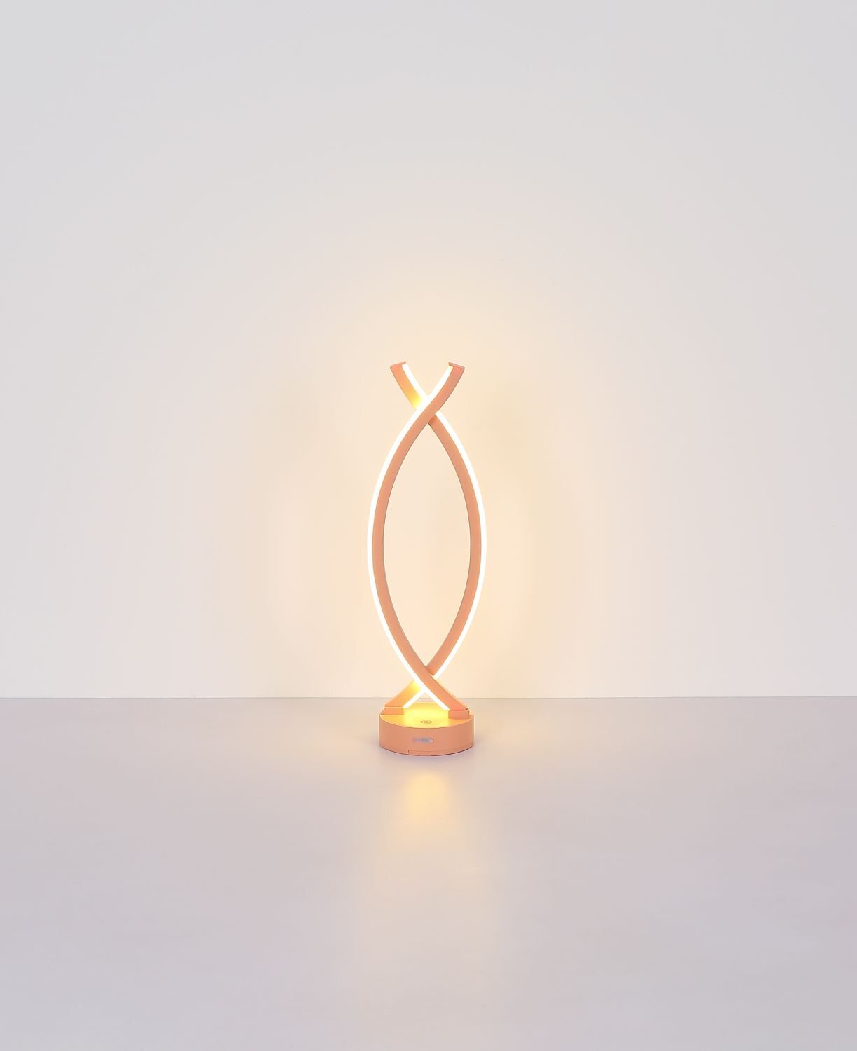 Nowoczesna lampa stołowa LED o spiralnym kształcie, emitująca ciepłe światło. Podstawa lampy jest okrągła i w kolorze miedzianym.