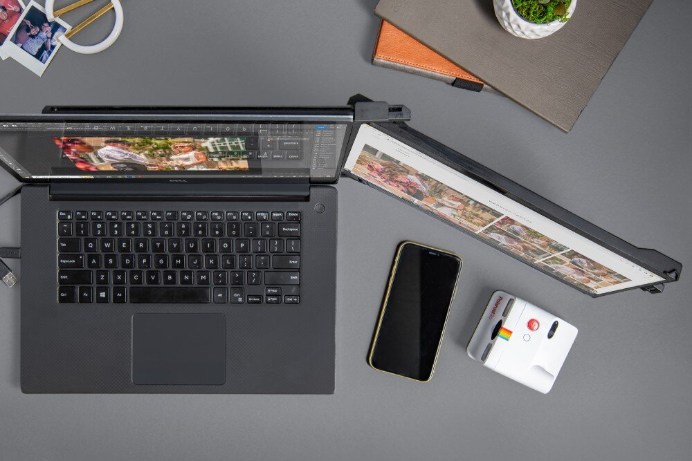 Monitor MOBILE PIXELS Duex Max DS Widok z góry na laptopa z dodatkowym przenośnym ekranem odchylonym do tyłu, obok leży smartfon, mały aparat fotograficzny i zamknięty notes