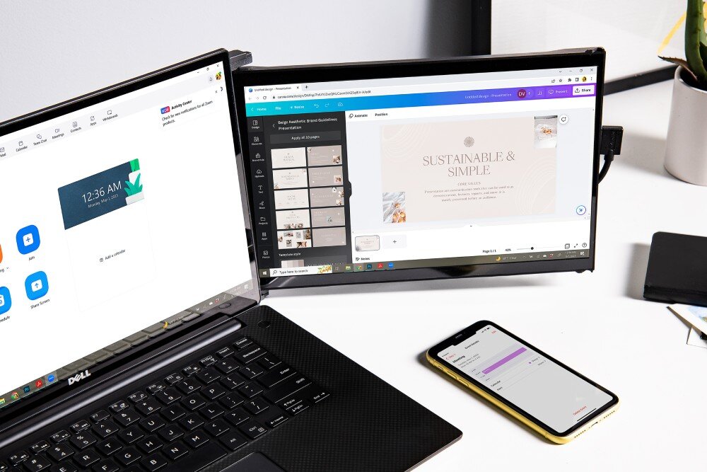 Monitor MOBILE PIXELS Duex Max DS Przenośny monitor zamontowany z prawej strony otwartego laptopa na jasnym biurku, obok leży smartfon z włączonym ekranem