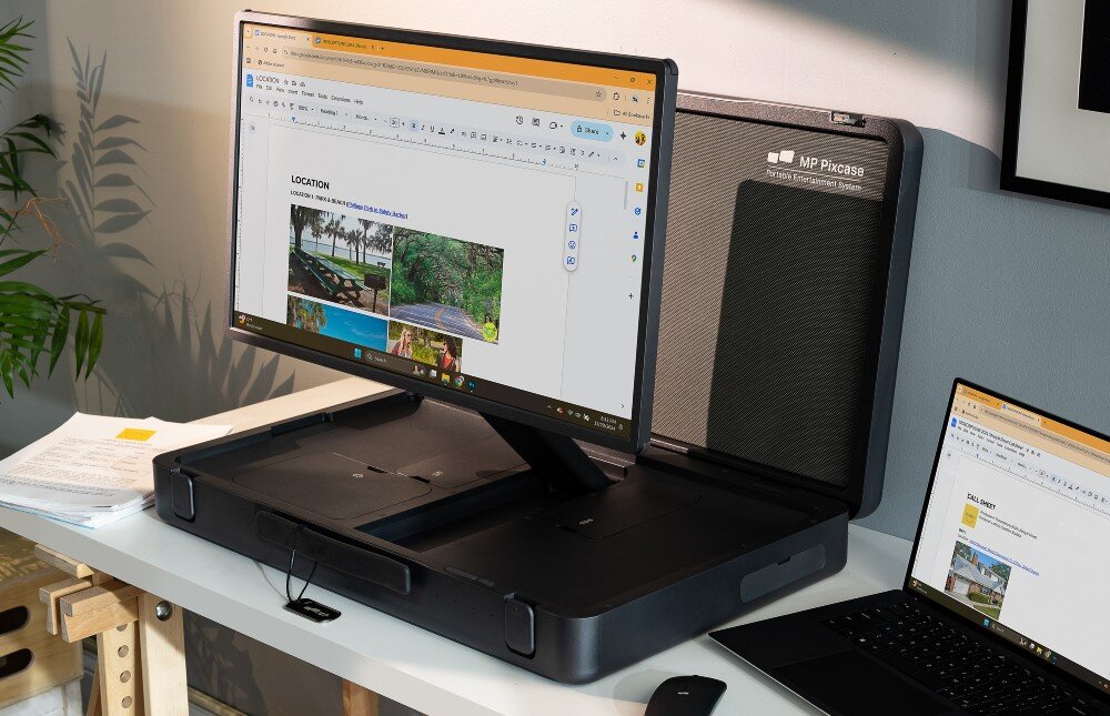 Monitor MOBILE PIXELS Pixcase Przenośny ekran zamontowany w walizce stojącej na biurkuObok leży otwarty laptop, myszka oraz dokumenty