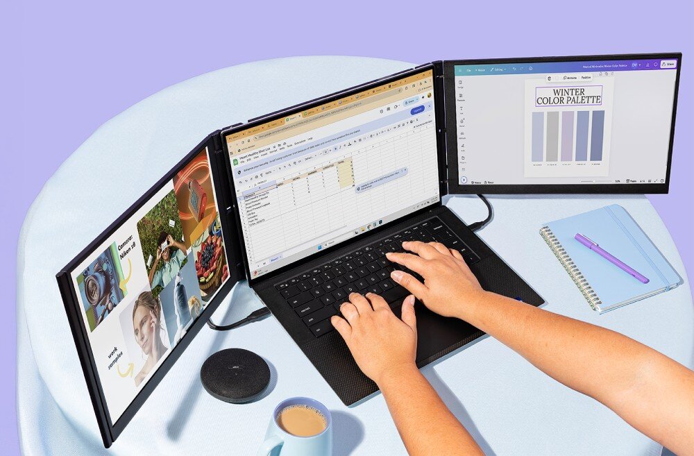 Monitor MOBILE PIXELS Trio 3 Pro Dłonie oparte na klawiaturze laptopa z dwoma dodatkowymi monitorami Wyświetlane są na nich arkusze, paleta barw i grafiki Obok leżą notes, długopis i kubek