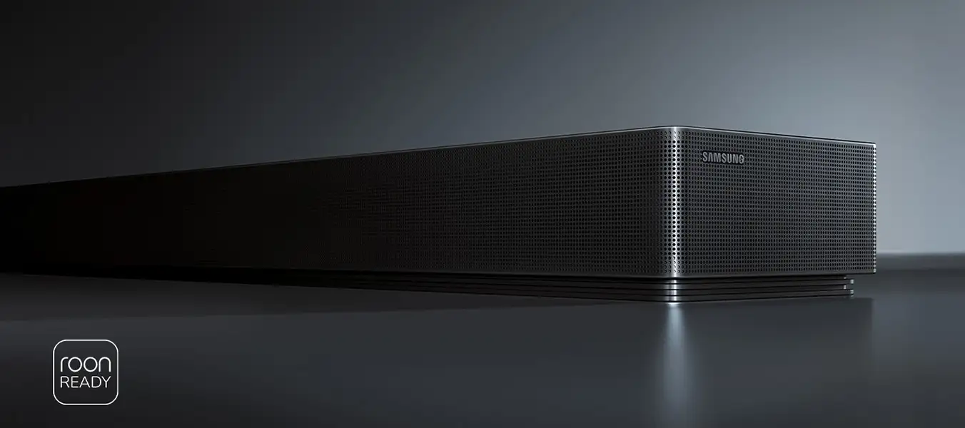 2026-hw-qs90h-kv-pc 1352x600 Grafitowo-czarny soundbar z widocznym logo \'SAMSUNG\' na przedniej części. W lewym dolnym rogu znajduje się napis \'roon READY\'.
