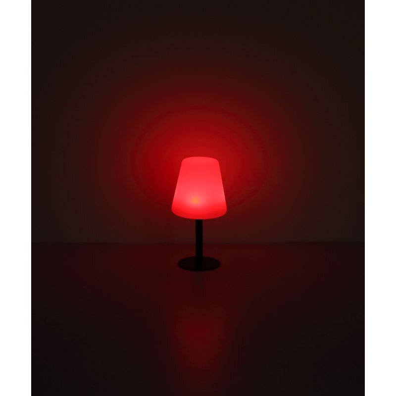 Na ciemnym tle widoczna jest lampa stołowa emitująca czerwone światło, z okrągłą podstawą i prostym trzonkiem.