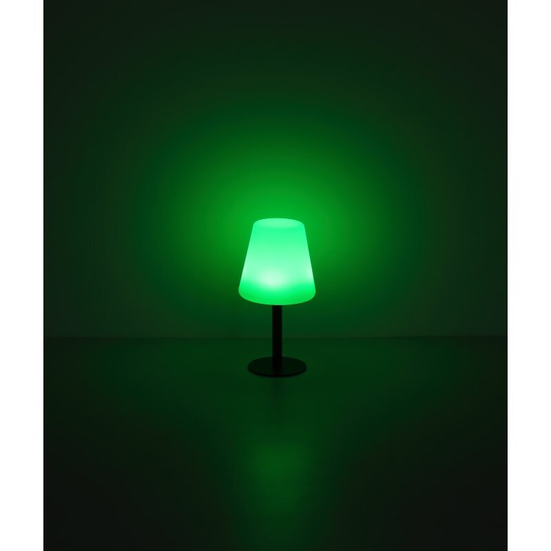 Na obrazie widać lampę stołową z zielonym kloszem, emitującą zielone światło. Lampa stoi na ciemnym tle, co podkreśla jej świecenie.