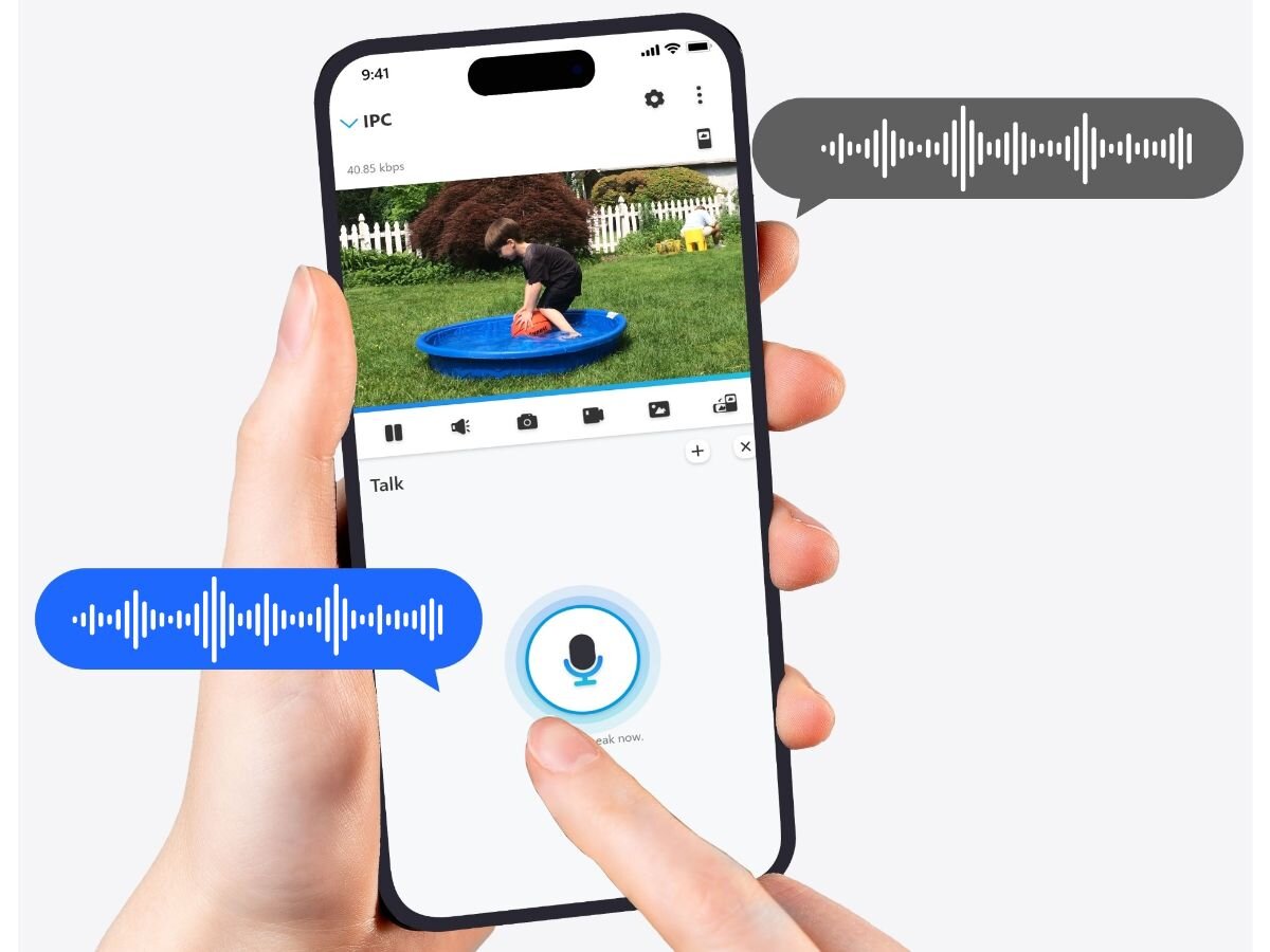 Osoba trzyma smartfon z aplikacją pokazującą obraz z kamery, na którym dziecko bawi się w niebieskim basenie na trawie. Na ekranie widoczne są ikony oraz przycisk mikrofonu z napisem \'Talk now\'.