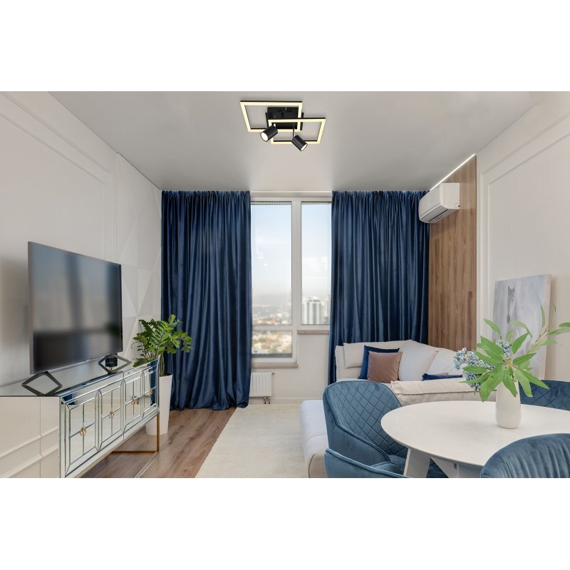 W nowoczesnym salonie znajduje się lampa sufitowa LED o geometrycznym kształcie. Pomieszczenie jest urządzone w stonowanych kolorach z niebieskimi zasłonami i dużym oknem.