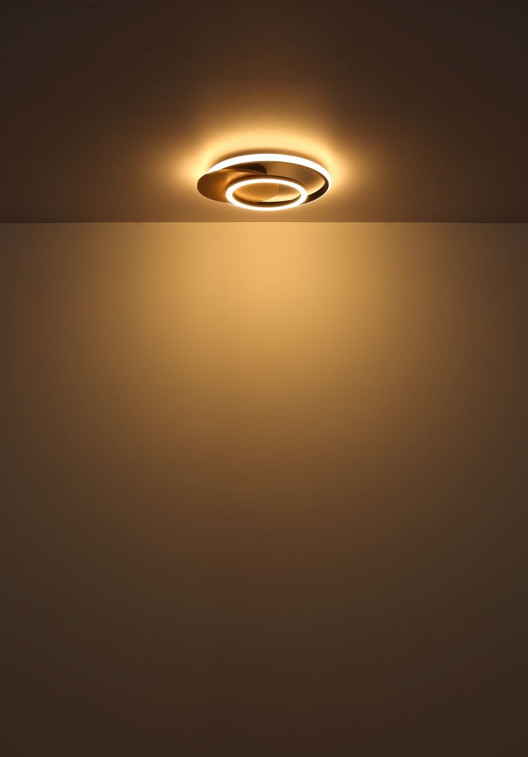 Na suficie zamontowana jest nowoczesna lampa sufitowa LED, emitująca ciepłe, rozproszone światło. Lampa ma okrągły kształt z kilkoma koncentrycznymi pierścieniami.