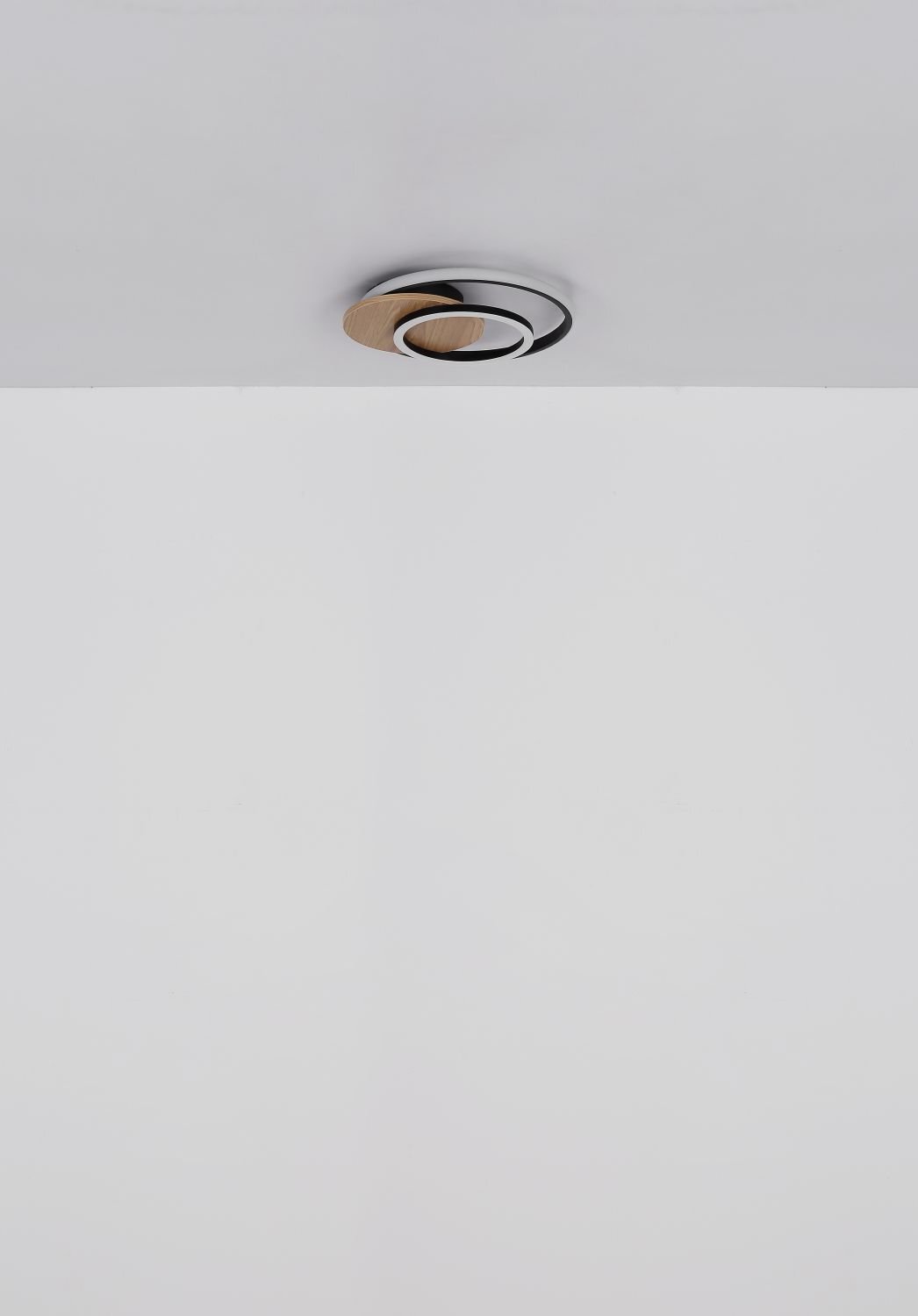 Na suficie zamontowana jest nowoczesna lampa sufitowa o okrągłym kształcie z elementami w kolorze drewna i metalu.