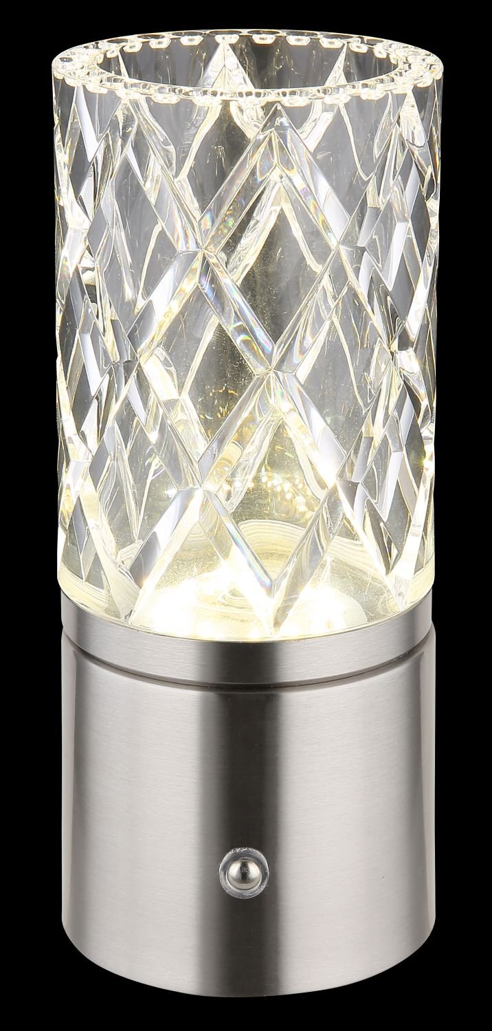 Lampa stołowa LED z przezroczystym, kryształowym kloszem o geometrycznym wzorze, osadzona na metalowej podstawie z przyciskiem. Światło wewnątrz klosza tworzy efektowne refleksy.