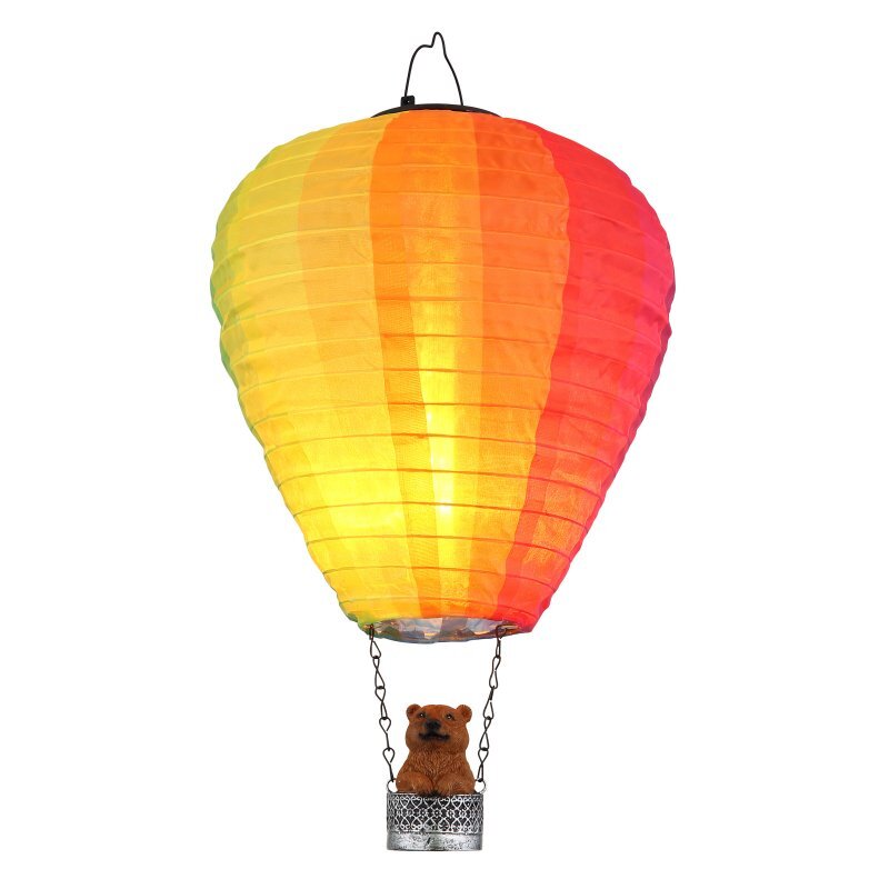 Lampa solarna w kształcie balonu na gorące powietrze z kolorowym kloszem w odcieniach żółci, pomarańczu i czerwieni. W koszu balonu znajduje się figurka misia.
