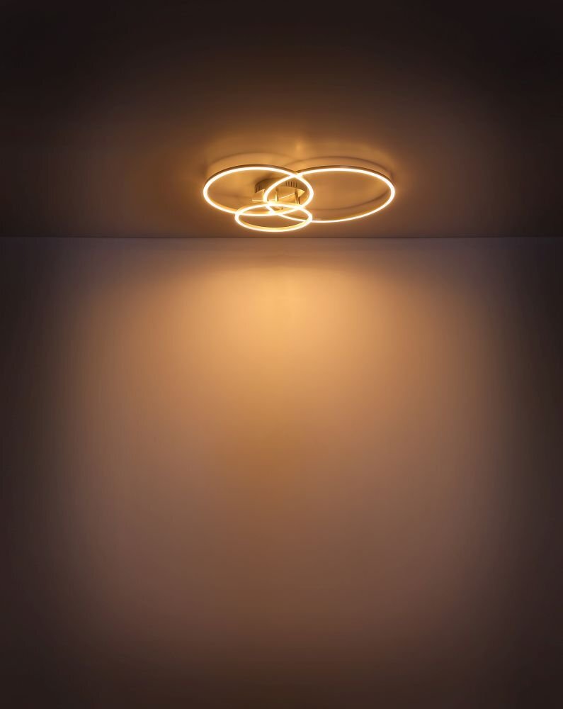 Na suficie zamontowana jest lampa sufitowa LED o nowoczesnym designie, składająca się z trzech okręgów emitujących ciepłe światło. Światło tworzy delikatny, rozproszony efekt na ścianie poniżej.