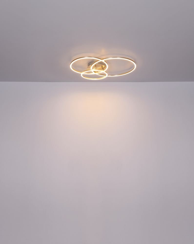 Na suficie zamontowana jest nowoczesna lampa LED z trzema okrągłymi, świecącymi obręczami. Światło lampy tworzy delikatną poświatę na suficie.