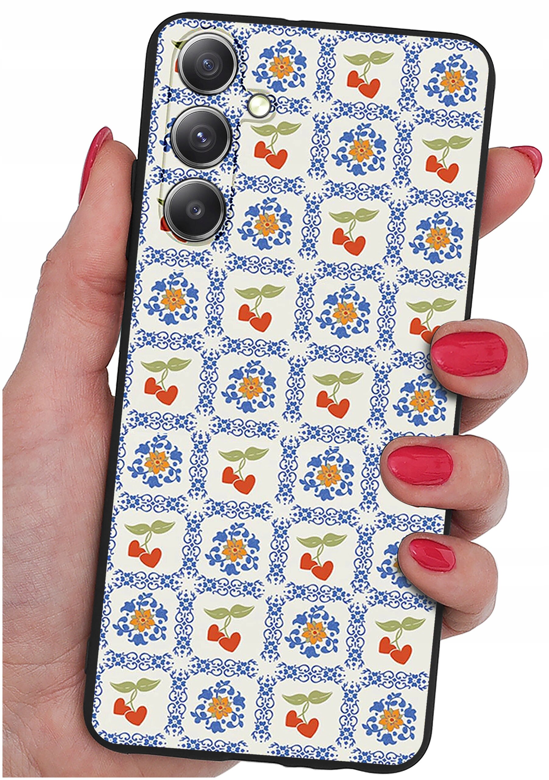 Osoba trzyma telefon z etui ozdobionym wzorem w niebieskie i pomarańczowe kwiaty oraz czerwone serca z zielonymi liśćmi. Etui ma wycięcia na trzy obiektywy aparatu i lampę błyskową.