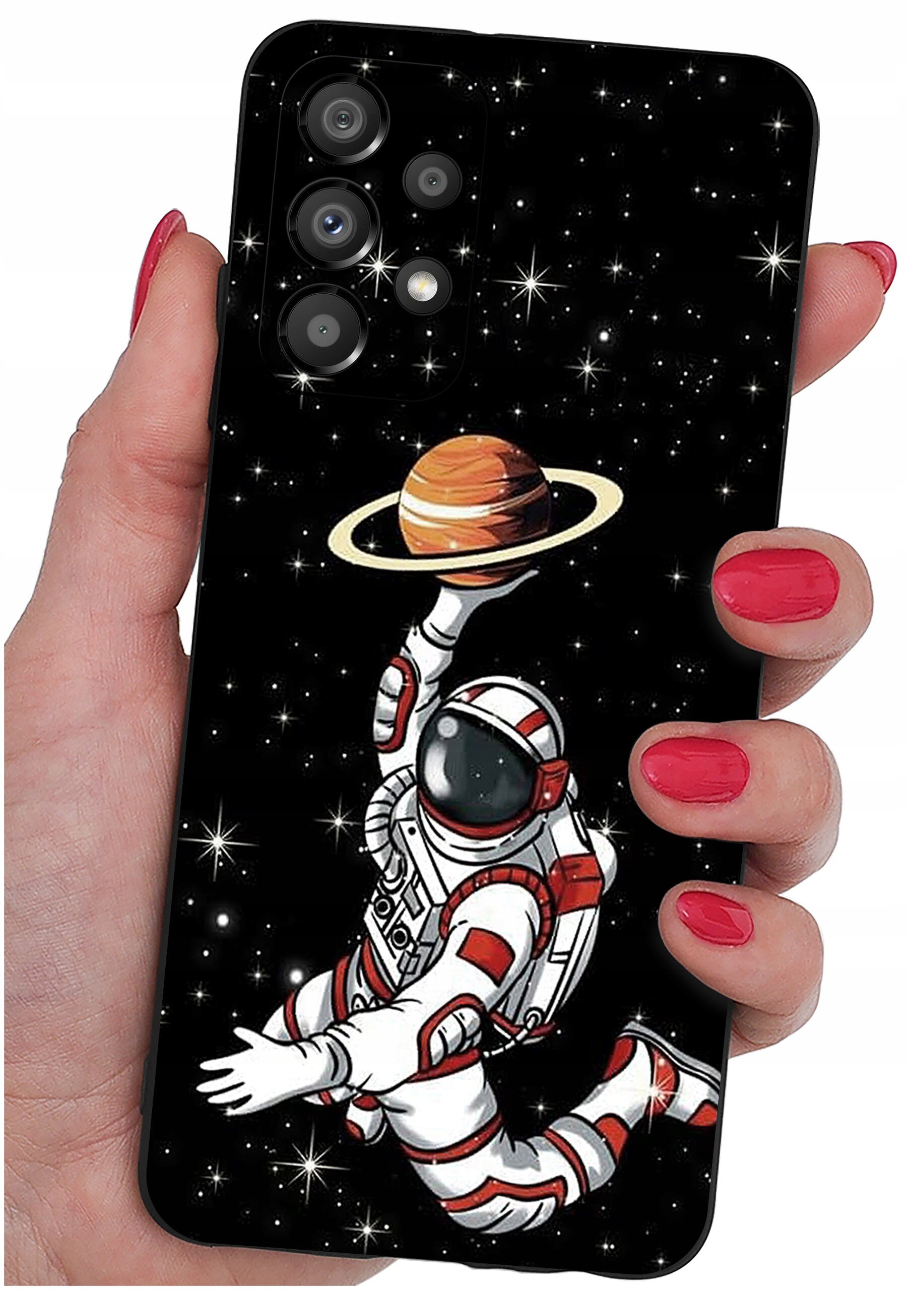 Etui na telefon z grafiką astronauty unoszącego planetę z pierścieniami na tle gwiazd. Etui trzymane jest w dłoni z pomalowanymi na czerwono paznokciami.
