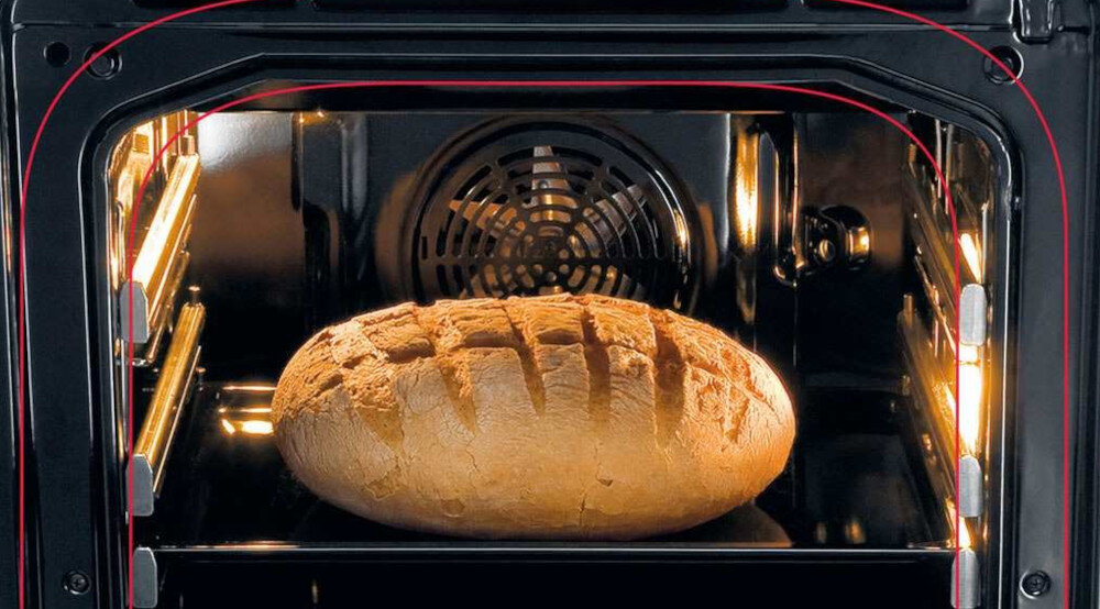 Wnętrze piekarnika z widocznym bochenkiem chleba na ruszcie. W tle widać wentylator piekarnika.