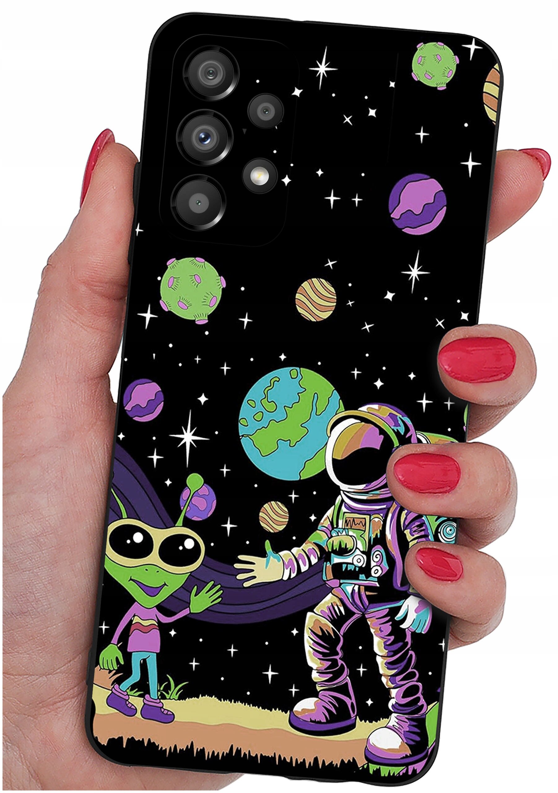 Etui na telefon z kolorowym wzorem przedstawiającym kosmonautę i zielonego kosmitę na tle kosmosu z planetami i gwiazdami. Etui trzymane jest w dłoni z pomalowanymi na czerwono paznokciami.