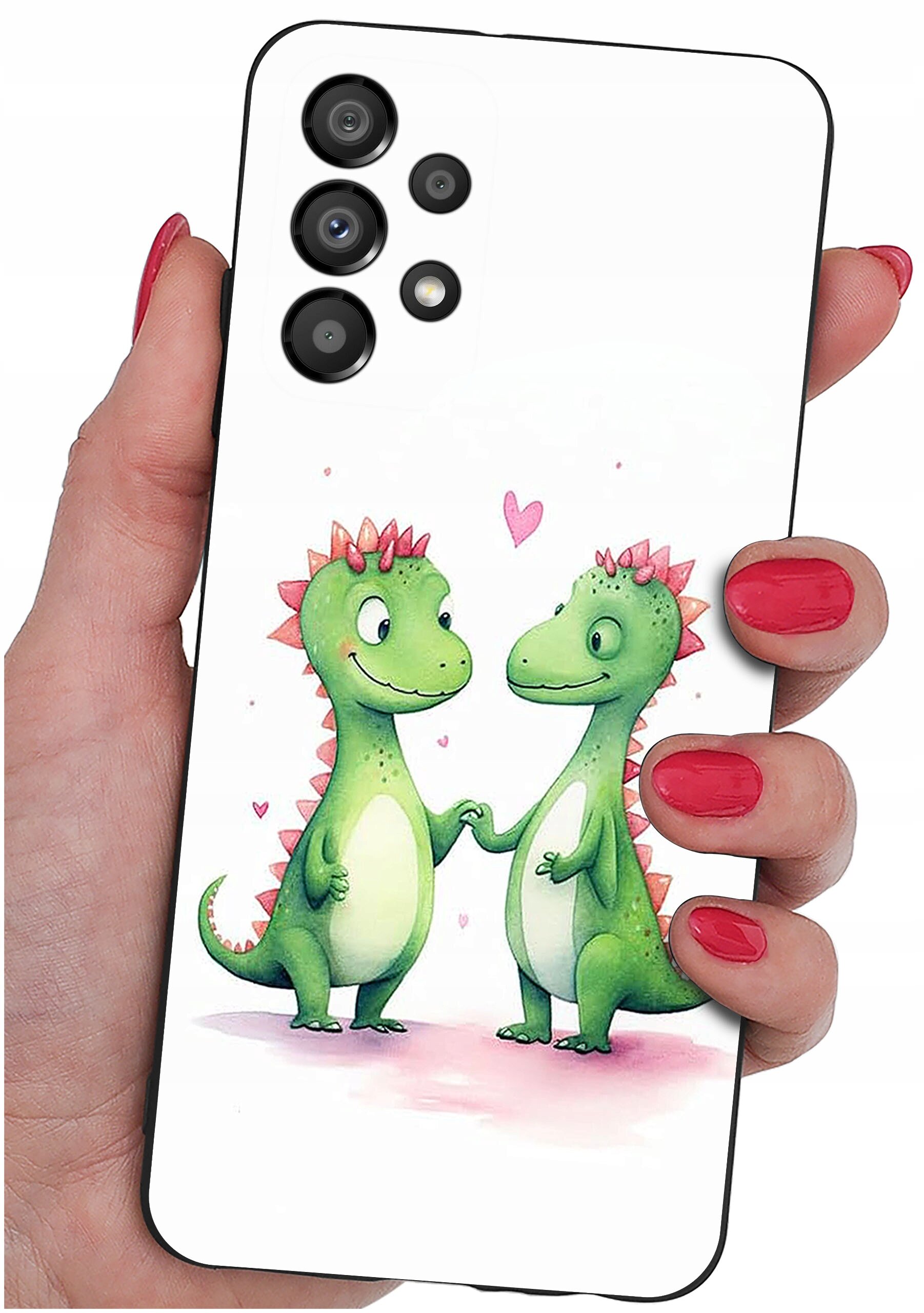 Etui na telefon z grafiką dwóch zielonych dinozaurów trzymających się za ręce, z różowymi serduszkami w tle. Etui jest trzymane w dłoni z pomalowanymi na czerwono paznokciami.